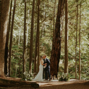 Couple wedding ceremony with 2 flower floor pieces on either side in forest